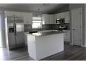 Stylish kitchen with stainless steel refrigerator, white cabinets, island, and granite countertops at 2487 Sw 170Th Loop, Ocala, FL 34473