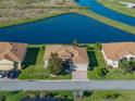 Aerial shot of a well-manicured lawn, brick driveway, and a tranquil pond behind the property at 3014 Ashton Palms Dr, Lake Wales, FL 33859