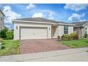 Charming single-story home featuring a two-car garage, white front door, brick driveway, and well-maintained landscaping at 336 Summer Squall Rd, Davenport, FL 33837