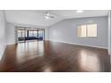 Spacious living room featuring beautiful dark hardwood floors, vaulted ceilings, and sliding glass doors to the patio at 4016 Cypress S Lndg, Winter Haven, FL 33884