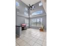 Living room showcases soaring ceilings, large windows for natural light, and neutral tile flooring at 438 Monroe Cir, Davenport, FL 33896