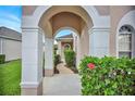 Charming arched entryway with lush greenery and a welcoming pathway leading to the front door at 451 Montara Dr, Davenport, FL 33897