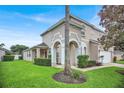 Stunning two-story home showcasing a manicured lawn, arched entryway, and pristine landscaping at 451 Montara Dr, Davenport, FL 33897