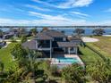 Back of home with a screened patio, swimming pool, and a view of a large body of water at 4717 Emerald Palms Ct, Winter Haven, FL 33884