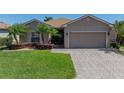 Single-story home with a brick driveway, tropical landscaping and an attached two car garage at 5325 Nicklaus Dr, Winter Haven, FL 33884