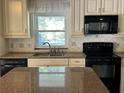 Custom kitchen featuring granite countertops, stainless faucet and black appliances at 5512 Meander Ln, Lake Wales, FL 33898