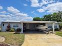 Charming home with a boat parked in the carport, under a bright blue sky at 121 Bonnie Dr, Auburndale, FL 33823
