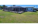 Enclosed pool with large screened enclosure, surrounded by green grass at 121 Bonnie Dr, Auburndale, FL 33823