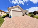 Exterior shot of the property showcasing the two-car garage and brick paved driveway at 1402 Colonial Ct, Winter Haven, FL 33884