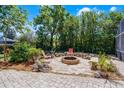 A backyard firepit area with brick pavers, chairs, and mature landscaping providing privacy at 2 Bridgewater Dr, Winter Haven, FL 33884
