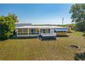 Back of yellow home featuring a metal roof and a deck, set in a spacious grassy yard at 225 Wes Mann Rd, Babson Park, FL 33827