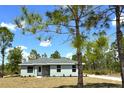 Well-maintained one-story home on a sunny day, with mature trees and a lush lawn at 3120 Oleander Dr, Indian Lake Estates, FL 33855