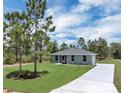Inviting single-story home featuring a spacious front lawn, classic gray exterior, and concrete driveway at 3120 Oleander Dr, Indian Lake Estates, FL 33855