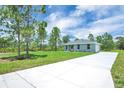 Quaint home with a well-kept lawn, a cozy gray exterior, and a clean concrete driveway at 3120 Oleander Dr, Indian Lake Estates, FL 33855