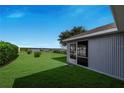 Backyard view featuring a screened in lanai and a well manicured lawn with a waterfront view at 4099 Island Lakes Dr, Winter Haven, FL 33881
