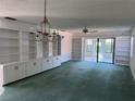Bright living room with large built-in shelving, ceiling fan, and sliding glass doors at 460 Pinehurst Ct, Winter Haven, FL 33884