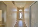 Inviting hallway with neutral-toned walls and tile flooring leading to a front door with decorative glass window at 509 Heather Glen Dr, Winter Haven, FL 33884