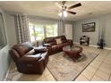 Inviting living room with plush leather seating, ceiling fan, and a large window overlooking the outdoors at 799 W Lake Otis Dr, Winter Haven, FL 33880