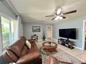 Relaxing living room with comfortable brown sofa, ceiling fan, and view to backyard at 799 W Lake Otis Dr, Winter Haven, FL 33880