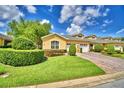 Charming yellow home featuring a manicured lawn and brick driveway leading to attached two-car garage at 2654 Rutledge Ct, Winter Haven, FL 33884