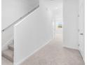 Bright hallway featuring neutral carpet, white walls, and staircase at 3265 Vesara Dr, Davenport, FL 33837