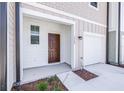 Inviting entryway with brown door, neutral siding, and manicured landscaping at 3269 Vesara, Davenport, FL 33837