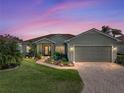 Charming single-story home with a well-maintained lawn, brick driveway, and inviting curb appeal at sunset at 4279 Ashton Club Dr, Lake Wales, FL 33859