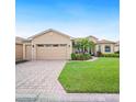 Charming single-story home with a well-manicured lawn, brick driveway, and attached two-car garage at 5200 Pebble Beach Blvd, Winter Haven, FL 33884