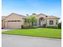 Inviting single-story home with lush landscaping, a brick walkway, and an arched entrance at 5200 Pebble Beach Blvd, Winter Haven, FL 33884