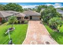 Charming home featuring a brick driveway, lush green lawn, and mature trees, creating a welcoming outdoor space at 571 Saint Andrews Rd, Winter Haven, FL 33884