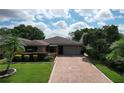 Charming home boasts a brick driveway, lush lawn, and mature landscaping at 571 Saint Andrews Rd, Winter Haven, FL 33884