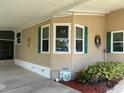 Exterior corner showcasing a window arrangement with green shutters and a small garden bed at the base at 6107 Grand Oaks Se Dr, Winter Haven, FL 33884
