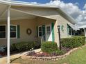 Close-up of a home's front entrance with green shutters, a storm door and landscaped garden bed at 6107 Grand Oaks Se Dr, Winter Haven, FL 33884