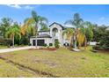 Landscaped exterior view of home showing the 2-car garage, palms, grass, and blue sky at 780 Gila Dr, Kissimmee, FL 34759