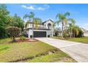 Exterior view of two-story home, driveway, with lawn and tropical palms at 780 Gila Dr, Kissimmee, FL 34759