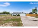 Charming single-story home with a spacious driveway, fenced backyard, and attached garage on a sunny day at 100 Ellen Ct, Winter Haven, FL 33884