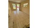 Empty living room with beige tile flooring, a front door, and two windows providing natural light at 128 11Th Wahneta W St, Winter Haven, FL 33880