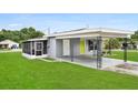 External home view featuring a grey exterior, well-maintained lawn, and covered carport at 2020 Bassedena W Cir, Lakeland, FL 33805