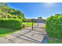 Gated home entrance with long driveway, well-kept lawn and mature trees at 2611 State Road 557, Lake Alfred, FL 33850