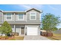 A well-kept townhome with gray siding, white trim, manicured landscaping, and an attached single-car garage at 310 N 1St Ave, Bartow, FL 33830