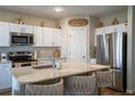 Modern kitchen featuring white cabinets, stainless steel appliances, and a cozy breakfast bar with stylish seating at 3440 Dahlia Dr, Haines City, FL 33844