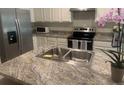 Kitchen island features a double sink and gray granite countertops at 386 Feltrim Reserve Blvd # 386, Davenport, FL 33837