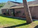 Side exterior view showcasing the brick facade, well-maintained lawn, and garden bed at 423 Greenfield Rd, Winter Haven, FL 33884