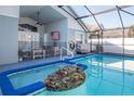 Sparkling pool with screened enclosure, featuring a rock waterfall spa and outdoor seating area at 8001 Arrow Creek Rd, Kissimmee, FL 34747