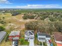 Aerial view showcasing the neighborhood with the home's solar panels and lush greenery in the background at 157 Golf Aire Blvd, Haines City, FL 33844