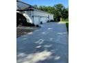 Side view of the 3-car garage with long driveway and meticulously maintained landscaping at 177 Costa Loop, Auburndale, FL 33823