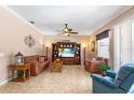Spacious living room with stylish tile flooring, large entertainment center, ceiling fan, and cozy seating at 177 Costa Loop, Auburndale, FL 33823