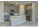 Modern kitchen featuring gray cabinets, a center island, stainless steel appliances, and tile backsplash at 2733 Attwater Loop, Winter Haven, FL 33884
