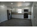 Bright kitchen with white cabinets, stainless steel appliances, and durable gray wood-look flooring at 3434 Avenue E Nw, Winter Haven, FL 33880