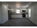 Bright kitchen with white cabinets, stainless steel appliances, and durable gray wood-look flooring at 3434 Avenue E Nw, Winter Haven, FL 33880